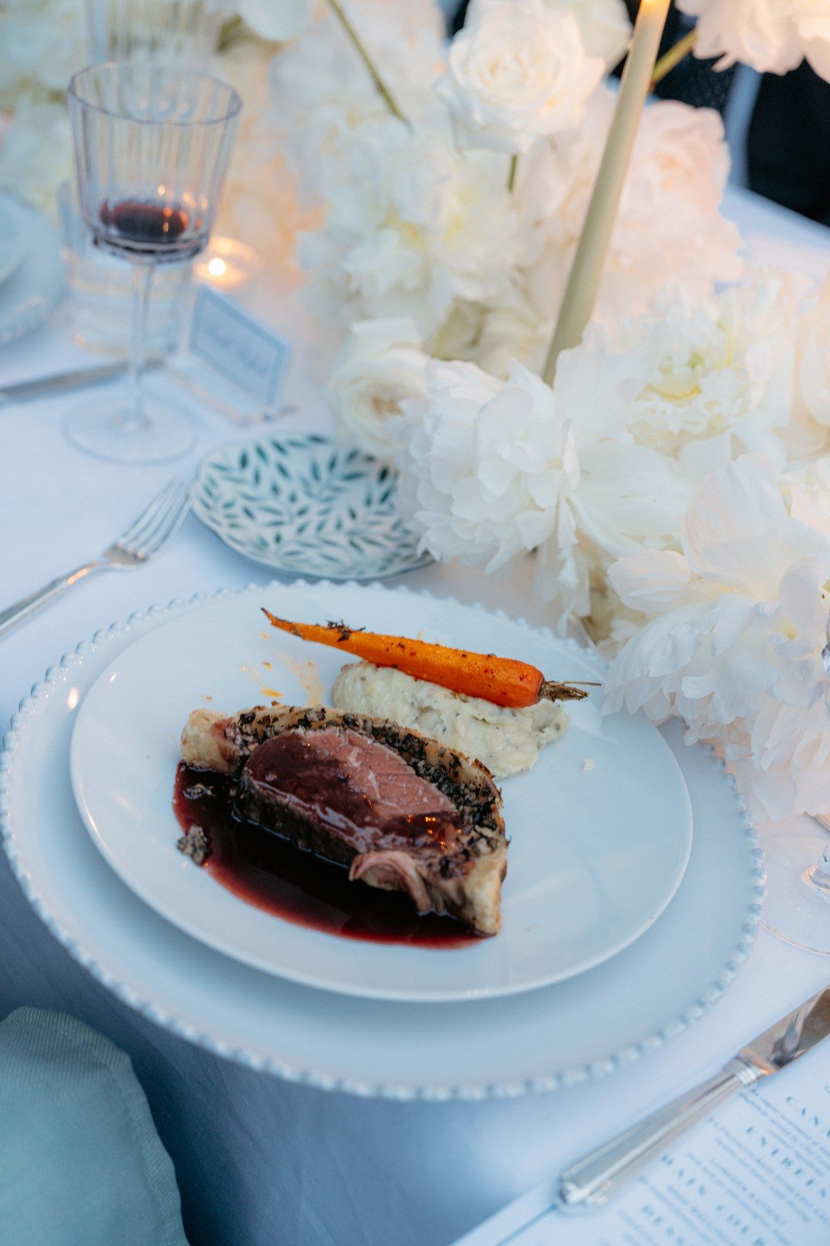 Glazed meat with carrots and fresh herbs on a white plate.