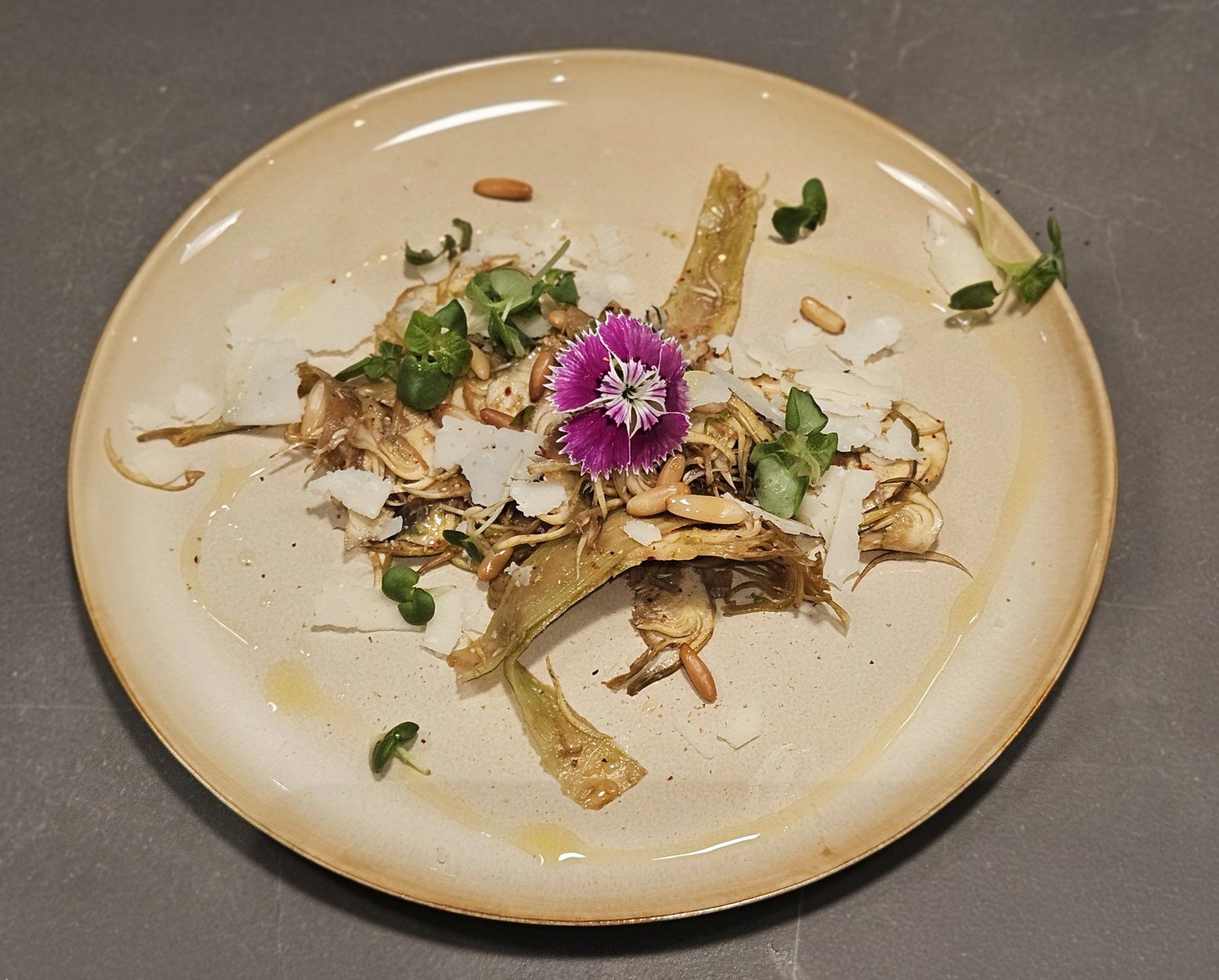 Red mullet fillet plated with glazed baby carrot, herb condiment and a single edible flower.