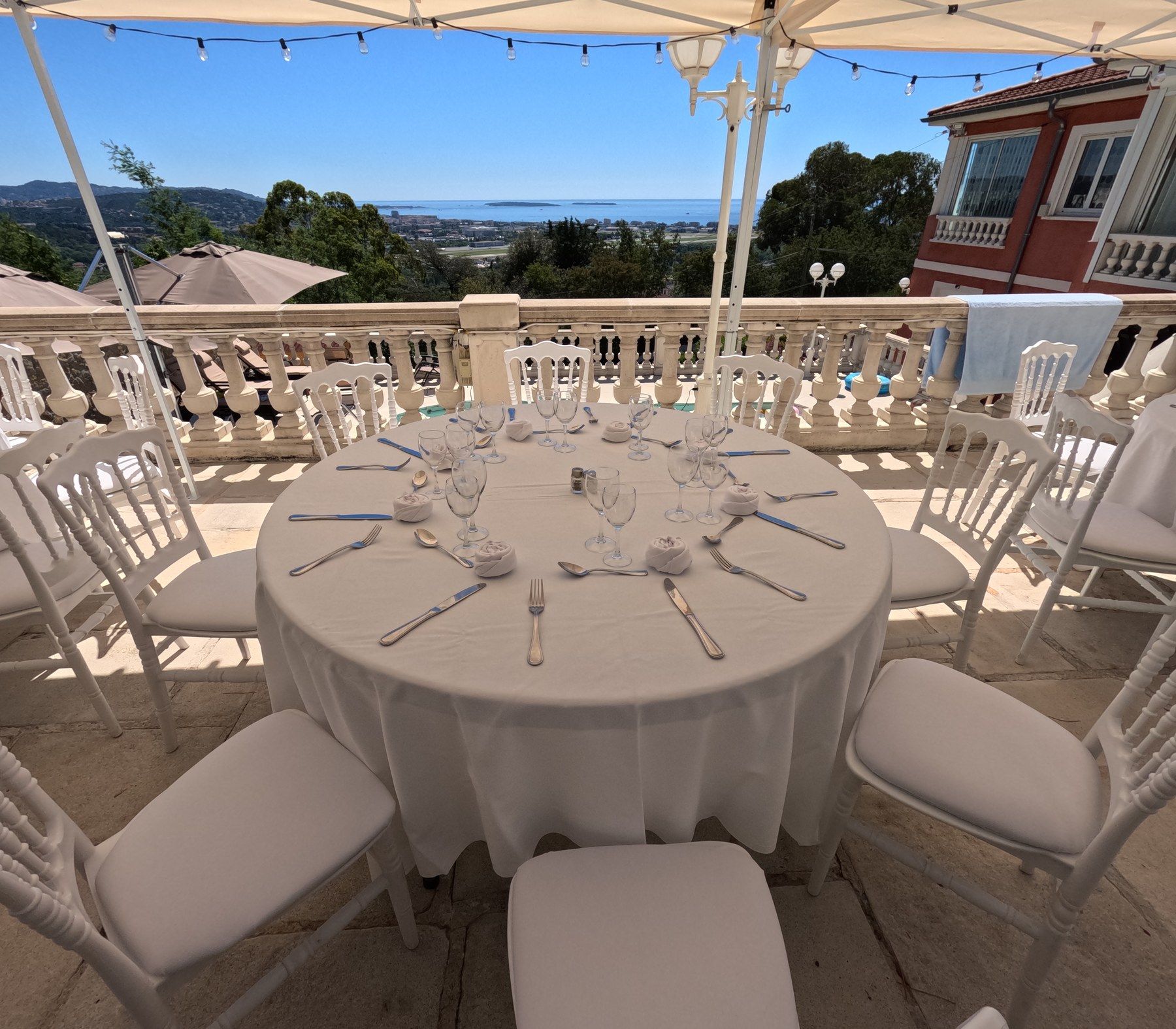 Riviera terrace before service: round tables, wicker chairs and sea view.