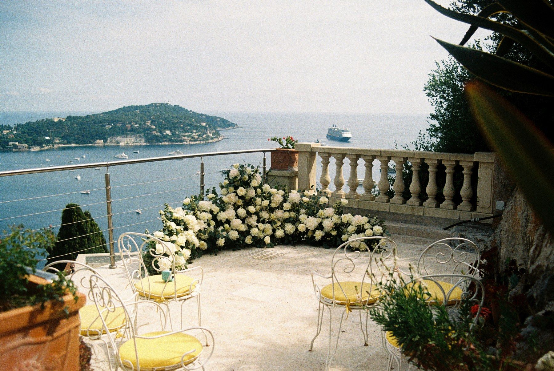 Riviera villa terrace, white-floral tablescape and Mediterranean view.